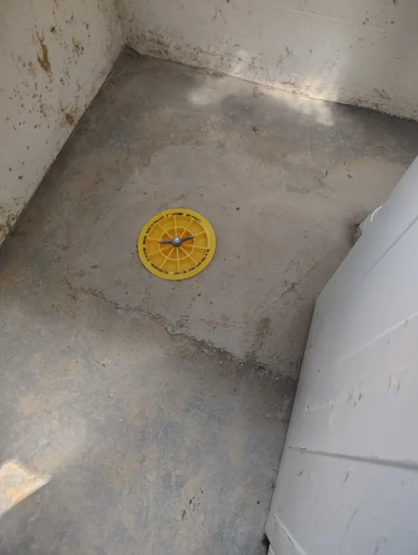 A finished concrete patch in a utility room floor after the backflow installation