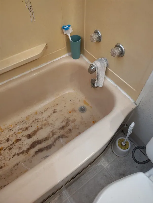 A bathtub holding standing water discoloured by a blocked drain