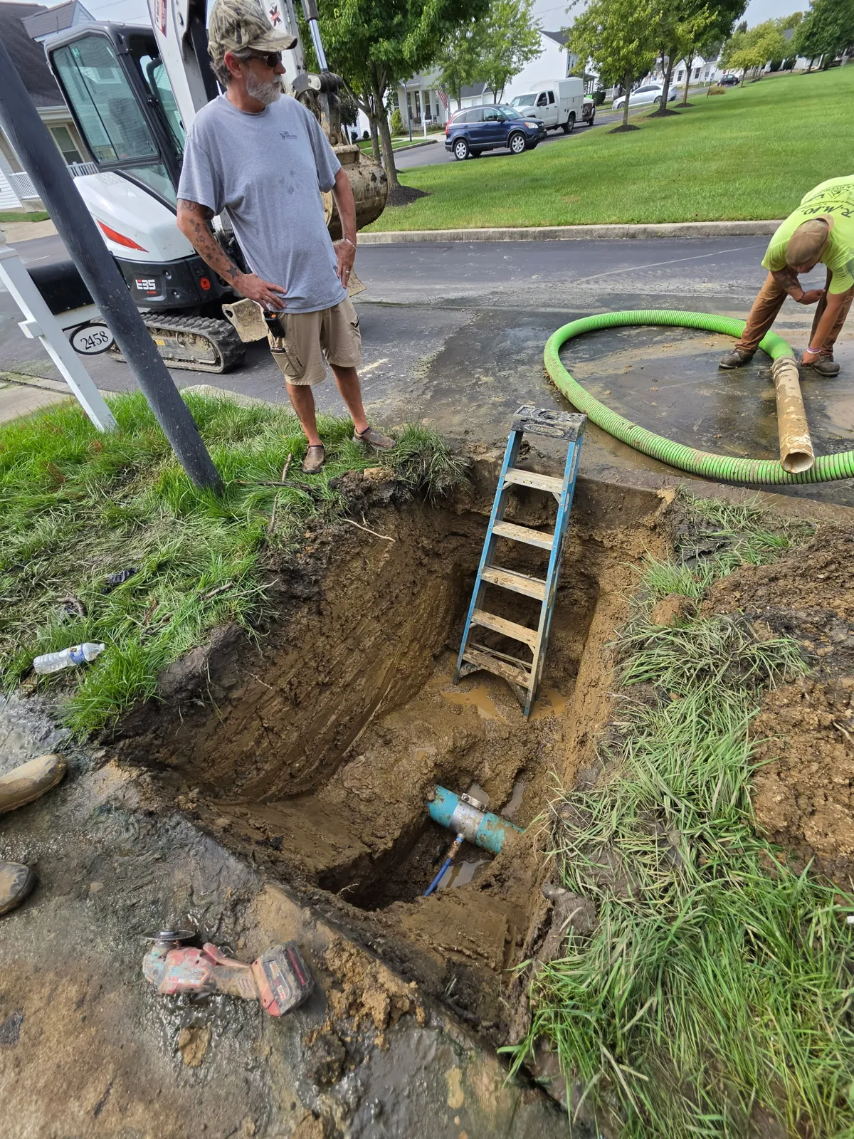 The DrainMaster crew working a narrow excavation at the curb with a service truck behind