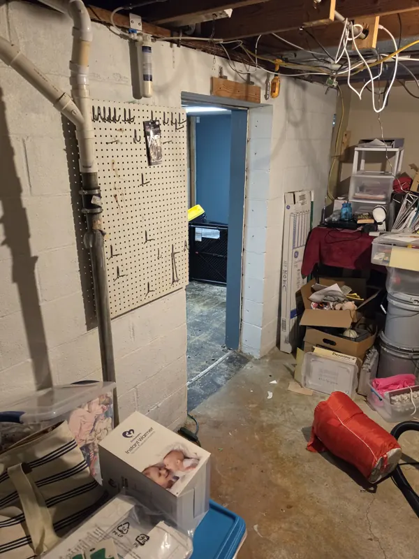 Old galvanized drain piping running down a basement wall