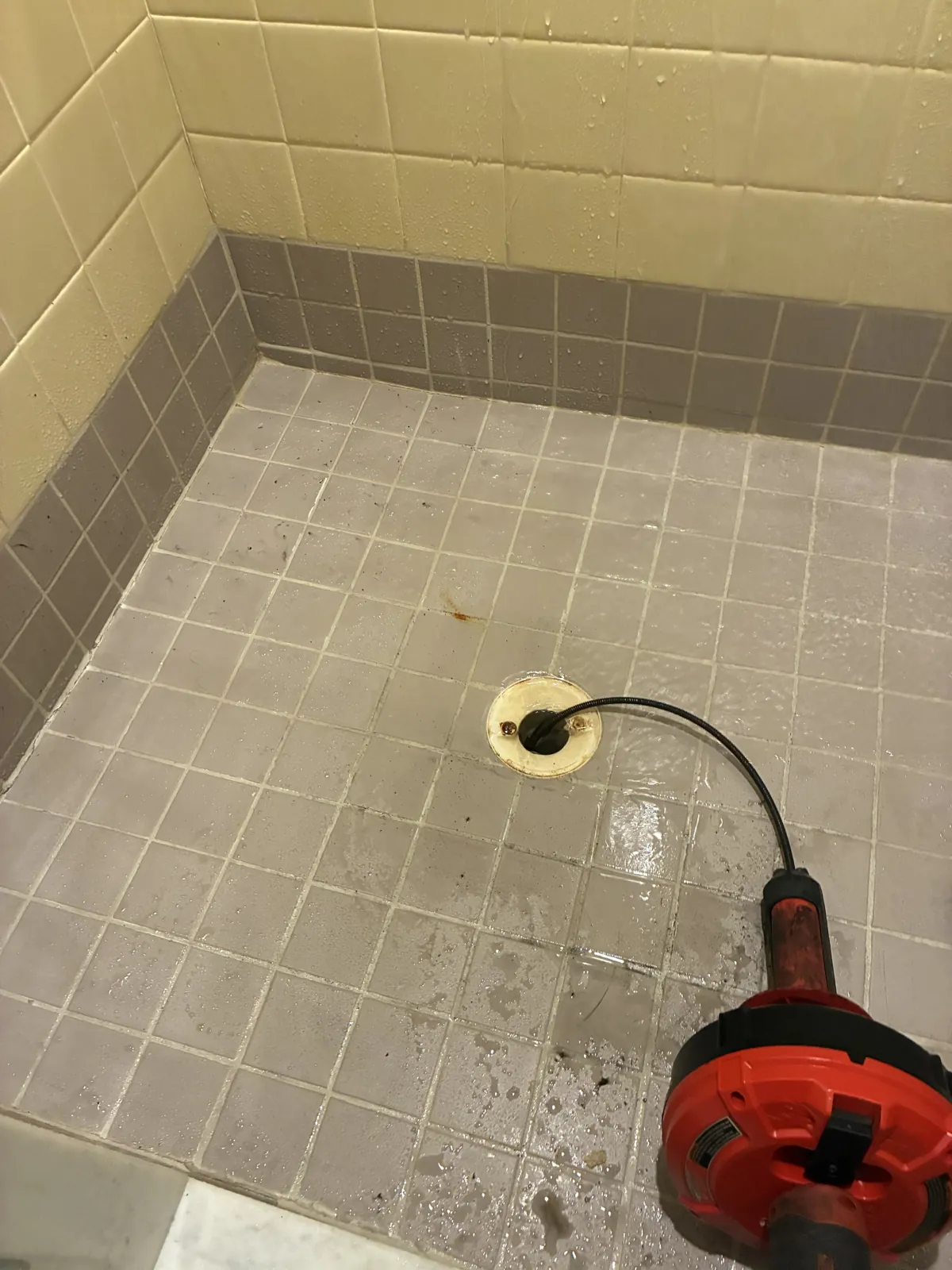 A drain cable fed into a tiled shower drain