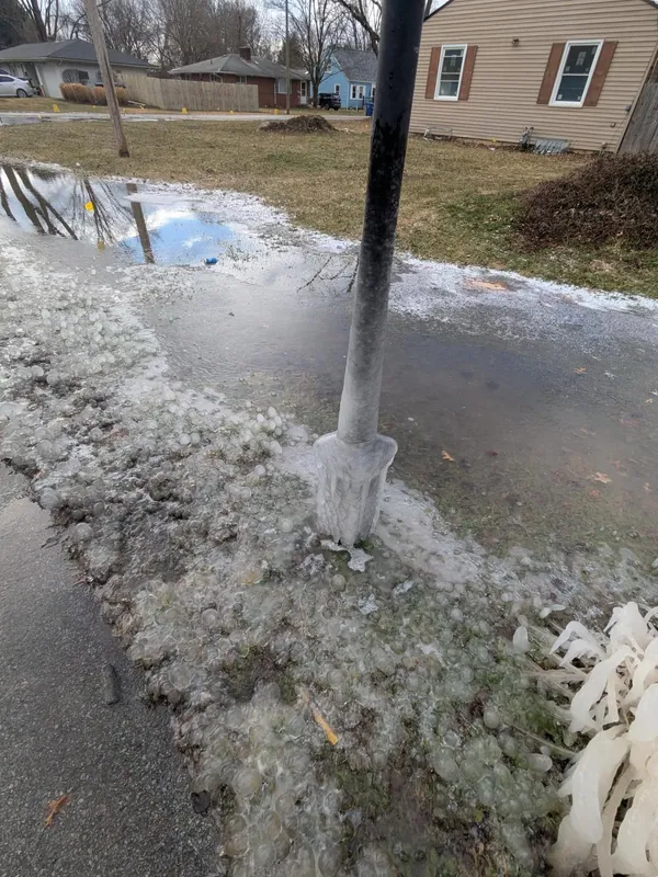 Water running across a residential driveway and street from a broken main