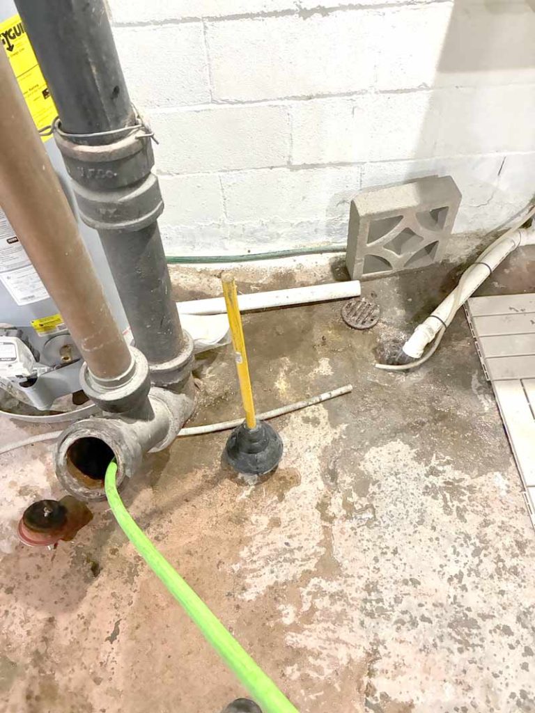 Basement drain pipe with plumbing snake during clog clearing