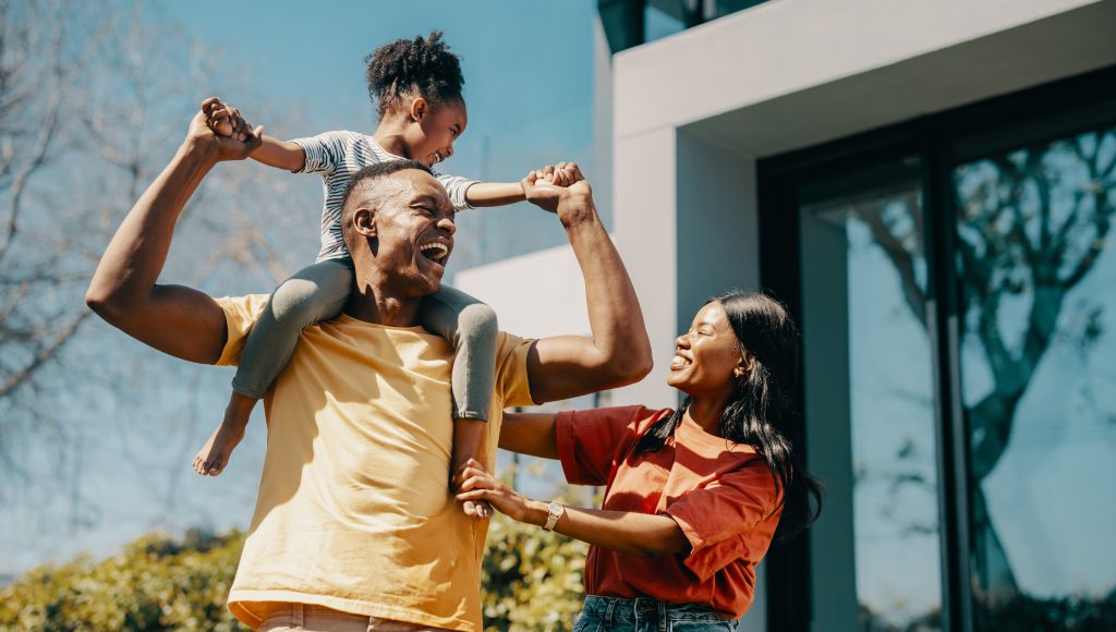 Happy family playing outside in front of their home