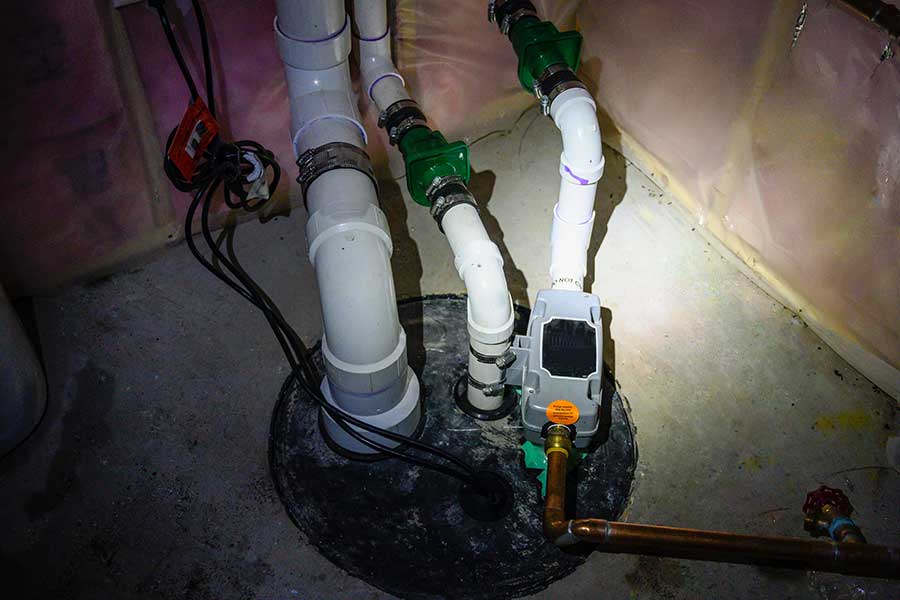 Basement sump pump system with connected discharge plumbing